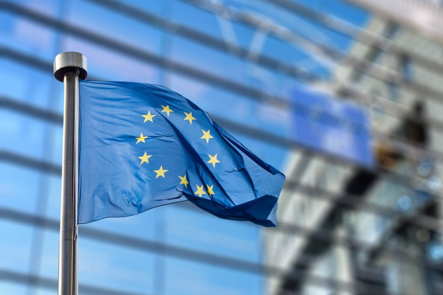 Zastava EU plapola v vetru. V ozadju stavba Evropskega parlamenta.