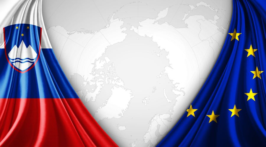Levo in desno zastavi RS in EU iz blaga, vsaka na svoji strani, na sredini je zemljevid sveta v sivi barvi.