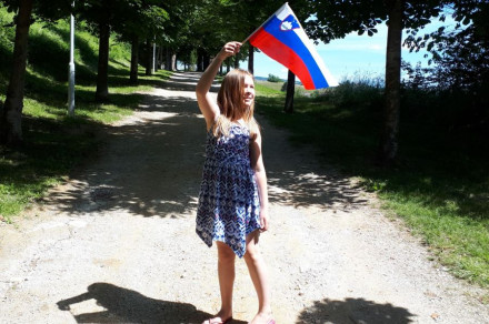 A little girl holds the flag on a stick.