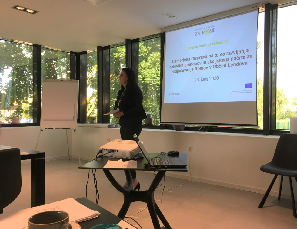 Govorka stoji pred platnom s projekcijo predstavitve