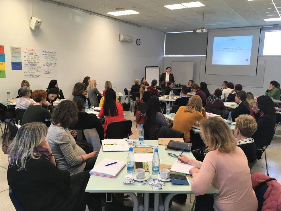 Udeleženci razprave sedijo za mizami po skupinah