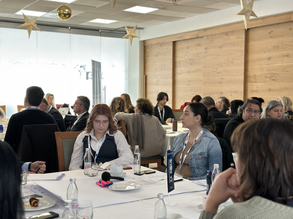 Udeleženci sedijo za mizo