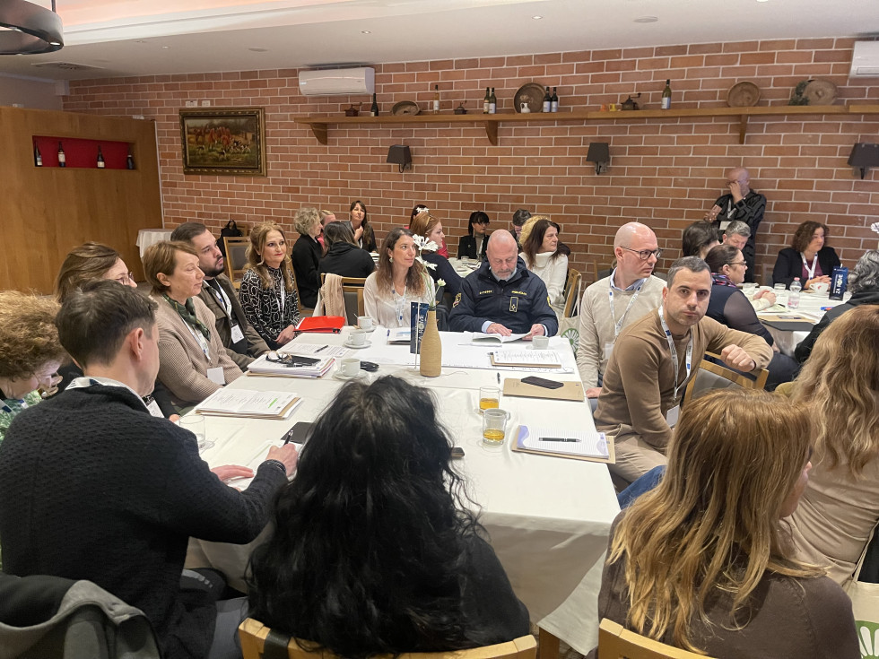 Udeleženci sedijo za mizami