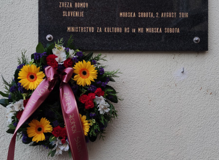 Spominska plošča - romske žrtve holokavsta, pod njo venec rož