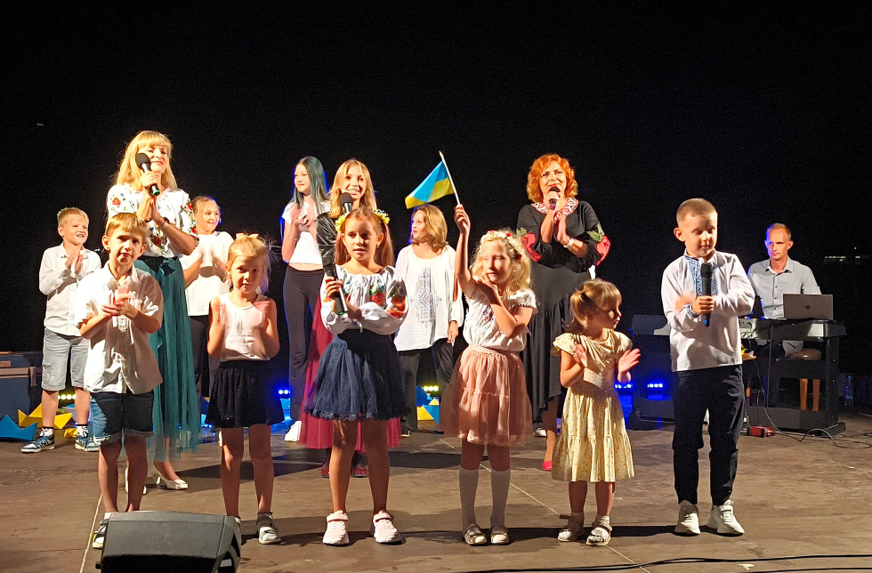 skupina otrok, ki pojejo in mahajo z zastavicami