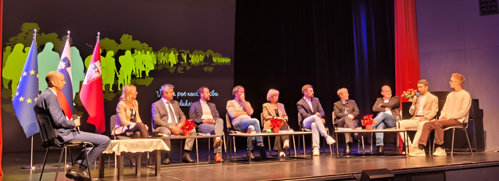 skupina ljudi sedi na stolih na odru in se pogovarja