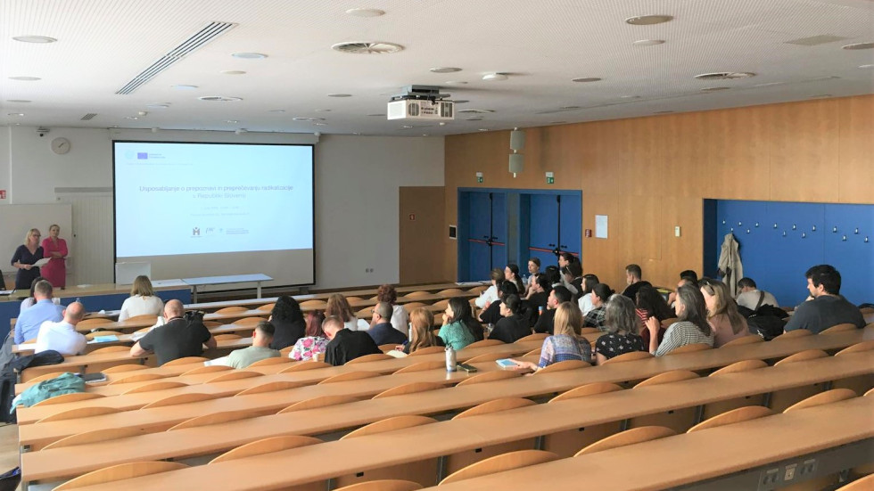 Skupina ljudi sedi v predavalnici in posluša predavanje