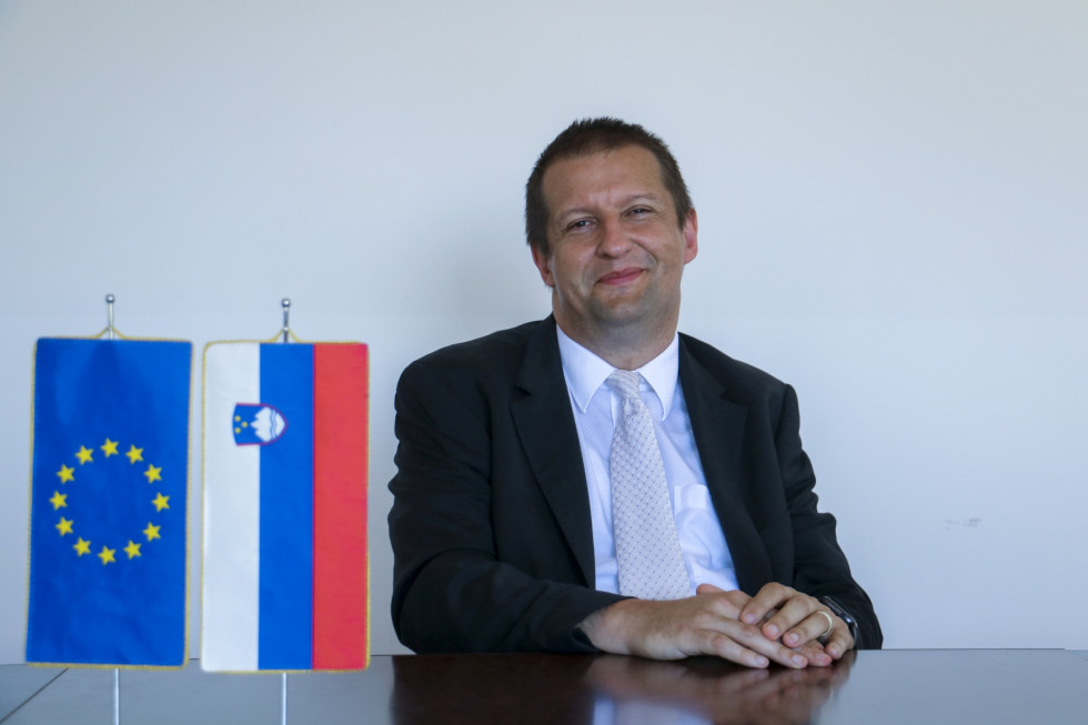 Na sliki je dr. Uroš Svete, direktor Uprave Republike Slovenije za informacijsko varnost. Levo od njega sta na mizi zastavici Evropske unije in Slovenije.
