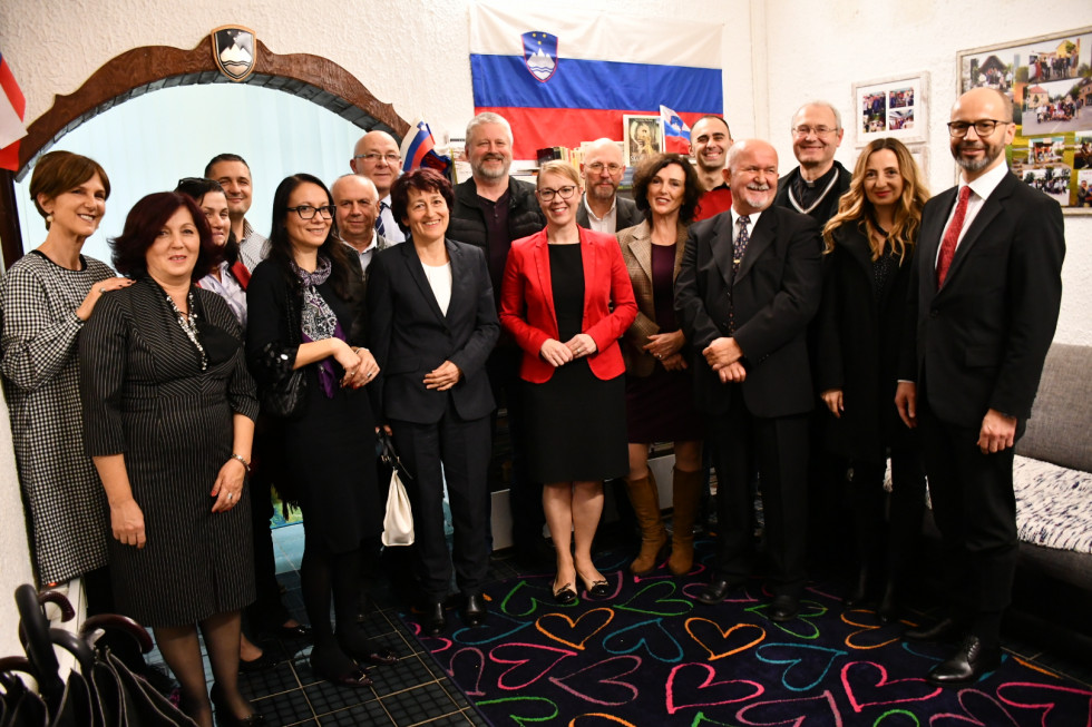Ministrica, predsednik in člani stojijo, za njimi slovenska zastava.