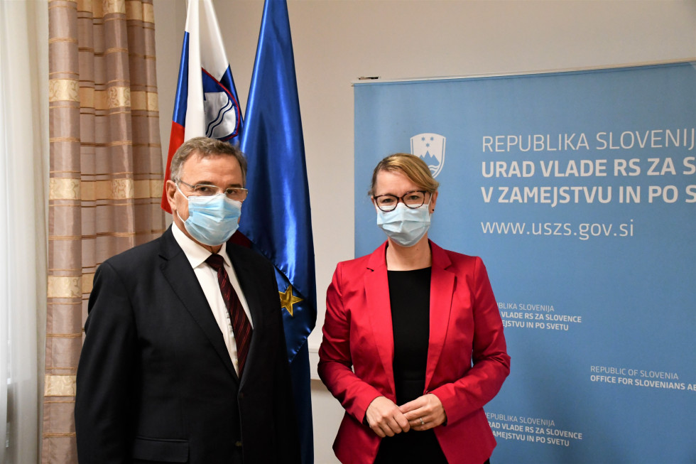 Ministrica in predsednik stojita, za njima slovenska in evropska zastava, na desni pano z logotipom urada.