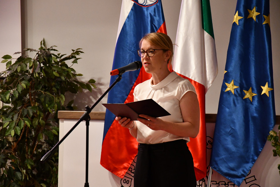 Med govorom, pri mikrofonu, za njo zastave.