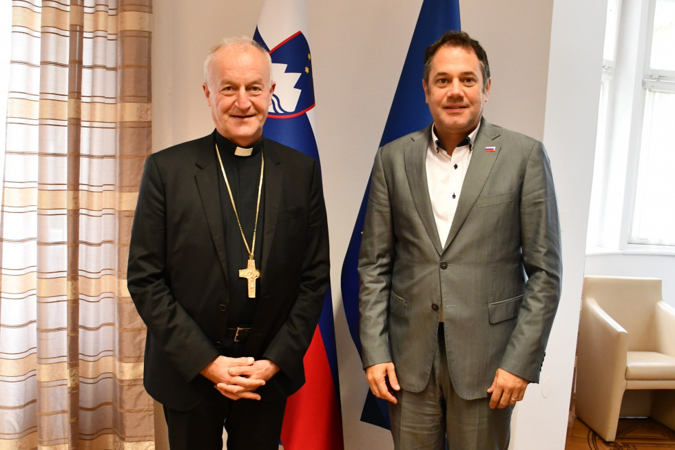 Škof dr. Anton Jamnik in minister Matej Arčon. Stojita pre slovensko in evropsko zastavo.