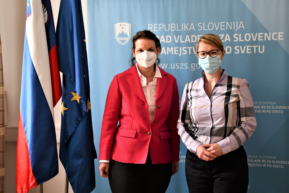Ministrica in veleposlanica pred napisom urada , ob strani slovenska zastava in zastava EU.