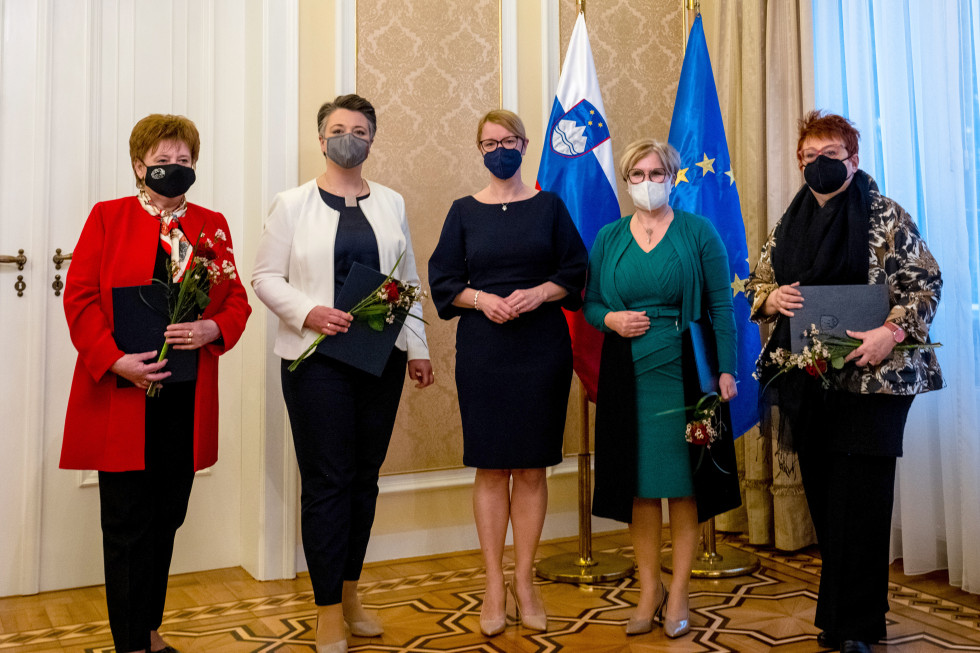 Ministrica in prejemnice, ki v rokah držijo zahvale in rožice. Za njimi slovenska in evropska zastava.
