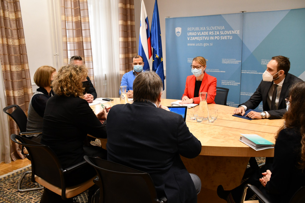 Ministrica in drugi udeleženci sestanka za mizo med pogovorom.