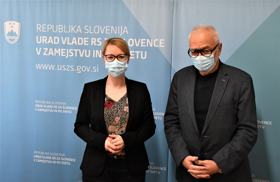 Ministrica in Žagar stojita pred modrim panojem na ketrem je napis Urad Vlade Republike Slovenije za Slovence v zamejstvu in po svetu.
