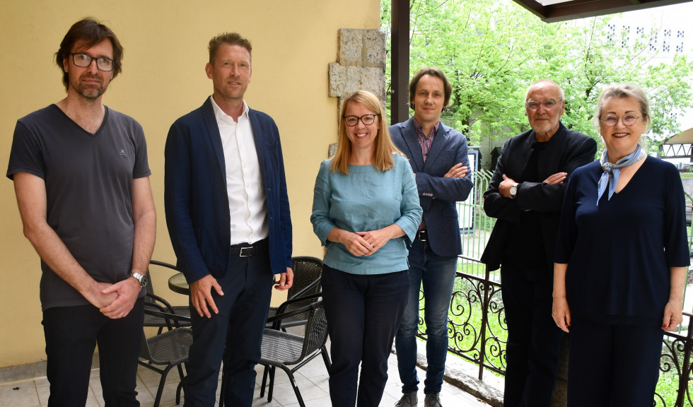 Aleš Vaupotič, Michael Karrer, dr. Helena Jaklitsch, dr. Robert Simonišek, Valentin Oman in Elisabeth Oman stojijo zunaj, v ozadju stavba urada in zelenje.