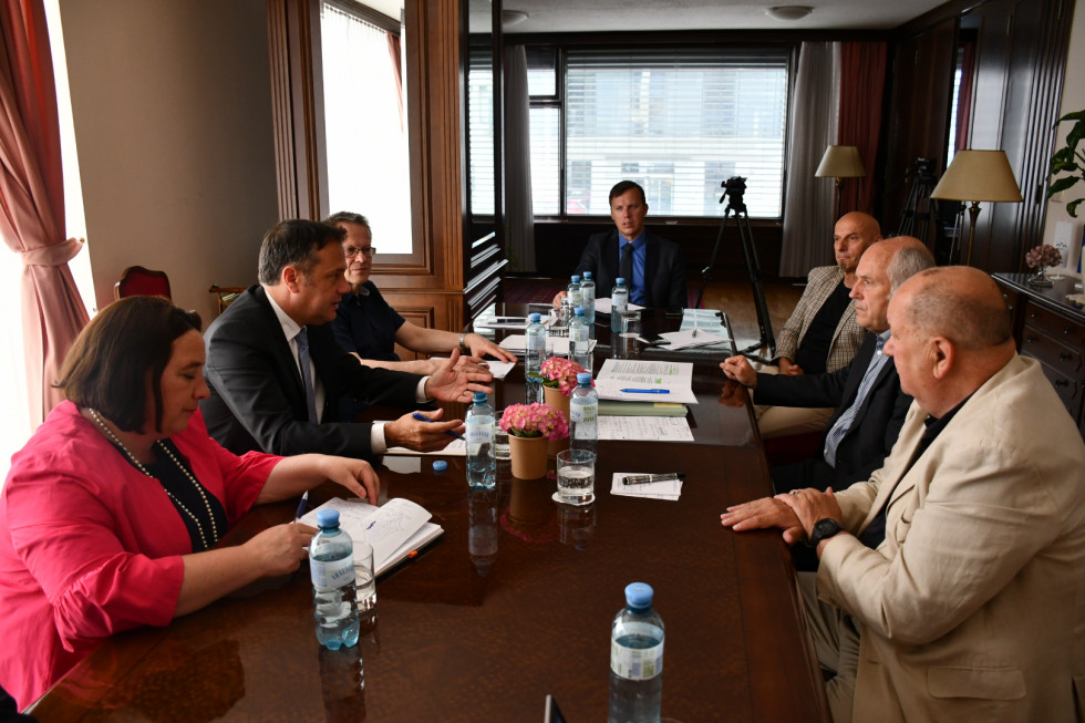 Minister, ekipa in predstavniki slovenske manjšine v Avstriji med pogovorom. Sedijo za mizo.