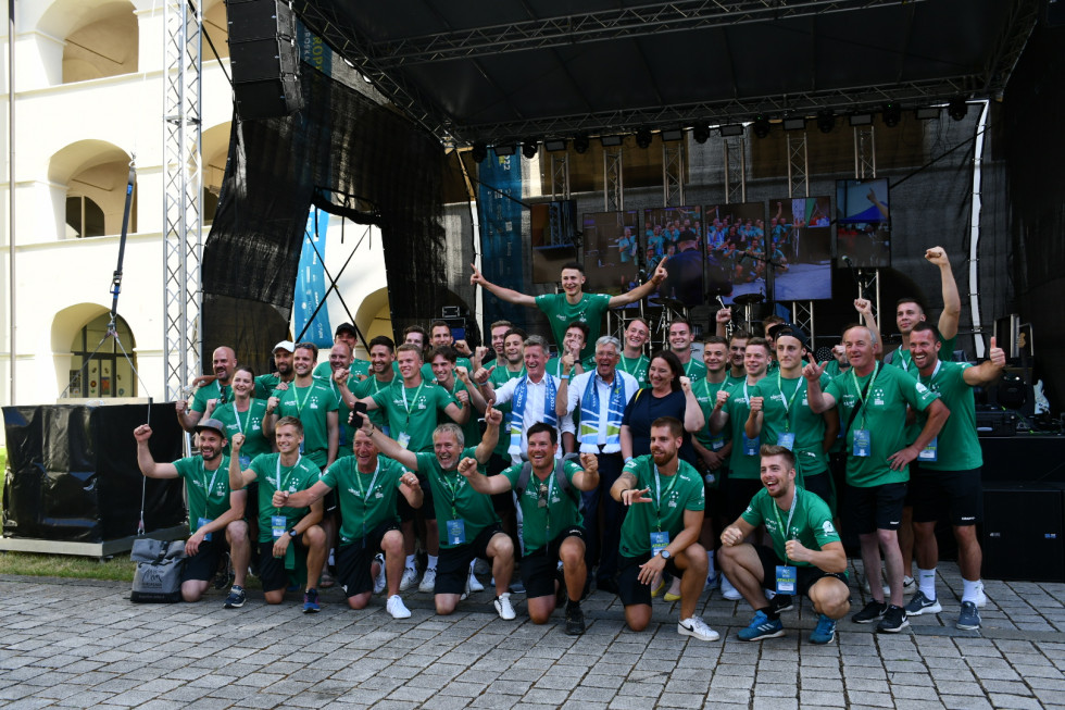 Državna sekretarka Humar z ekipo koroških Slovencev.Stojijo z dvignjenimi rokami. Vsi imajo zelene majice.