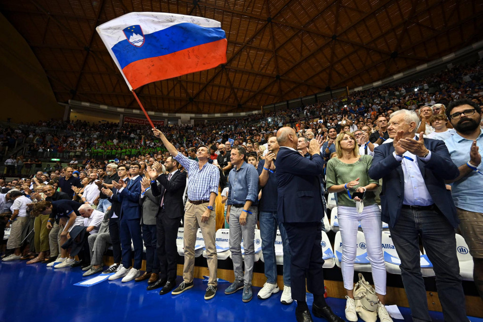 Predsednik Pahor in minister Arčon med gledalci na robu igrišča. Pahor vihti slovensko zastavo.