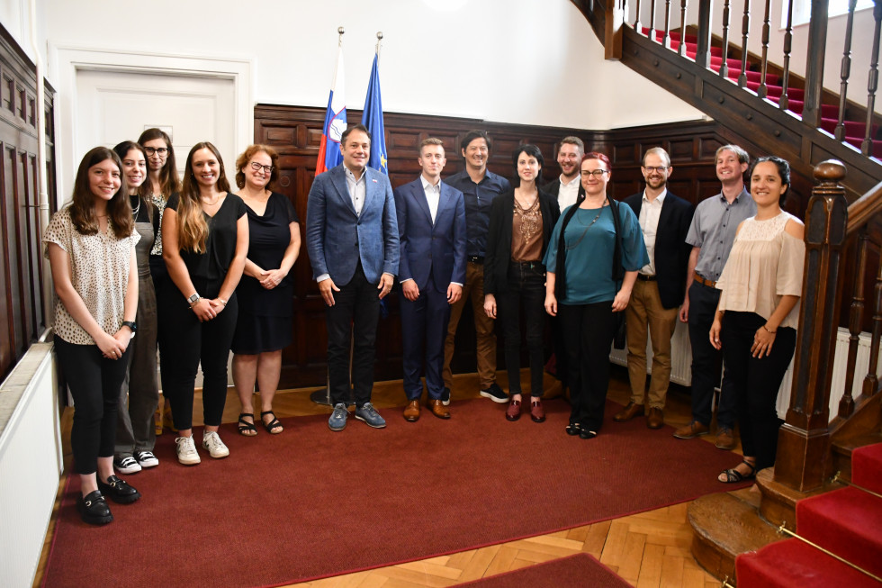 Minister z udeleženci sprejema, za njimi slovenska in evropska zastava.