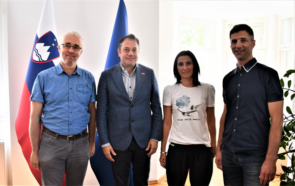 Koordinator projekta Danilo Jesenik Jelenc, minister Matej Arčon, strokovna delavka Magdalena Strmšek Buh in generalni tajnik Slovenske karitas Peter Tomažič. stojijo, v ozadju slovenska in evropska zastava.