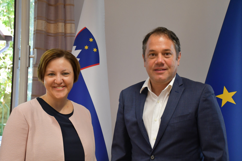 Doc. dr. Ana Polak Petrič, Matej Arčon stojita pred slovensko in evropsko zastavo.