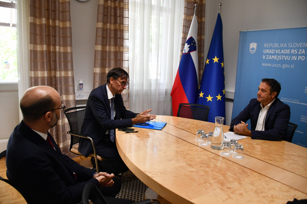 Marko Tavčar, Jan Leopoli in Matej Arčon sedijo za mizo, v ozadju slovenska in evropska zastava.