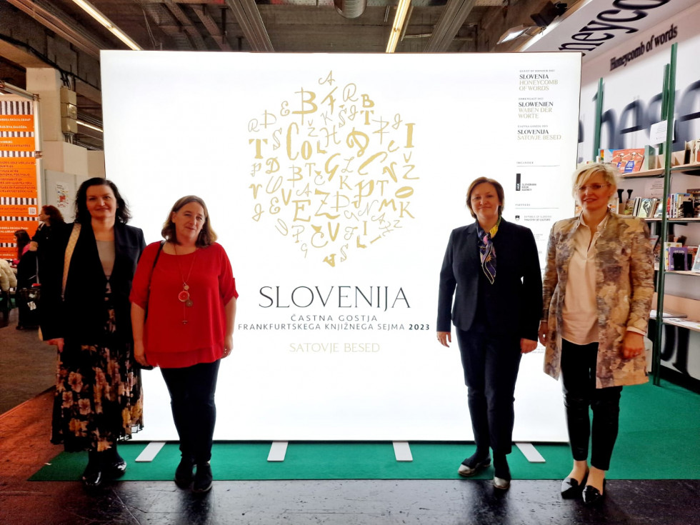 Državna sekretarka pred emblemom slovenskega paviljona an sejmu.