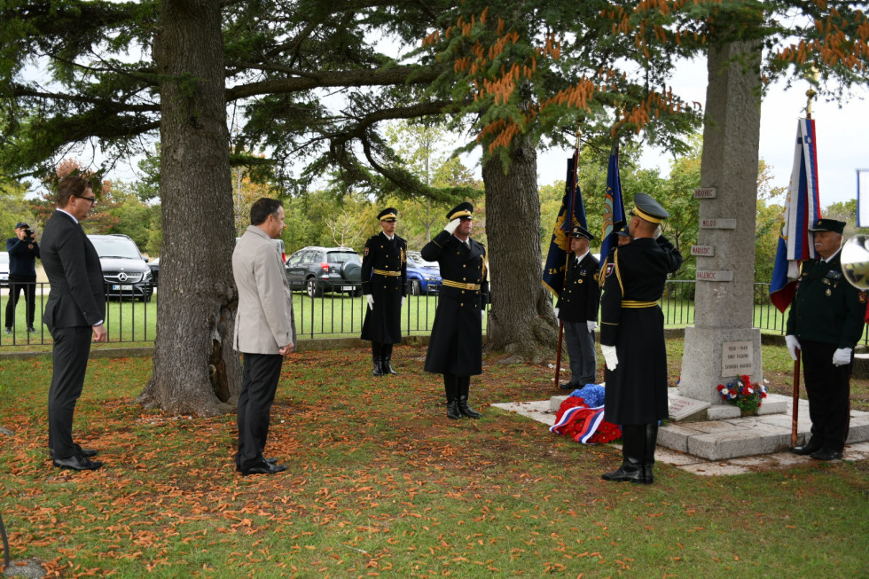 Minister Arčon pred spomenikom na gmajni, kjer je položil venec. Ob spomeniku vojaki.