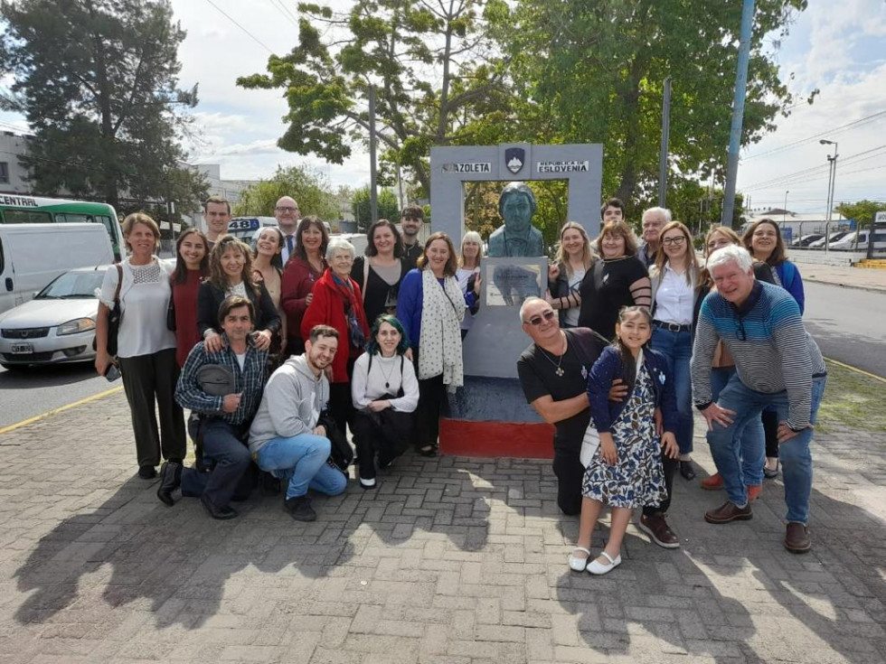 Državna sekretarka na slovenskem trgu s člani društva Bernal. Skupinska slika, ne sredi spomenik Francetu Prešernu in slovenski grb.