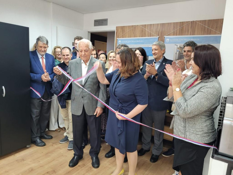 Državna sekretarka Humar in častni predsednik Černugelj na odprtju Slovenskega doma Triglav. Med prerzom traku.