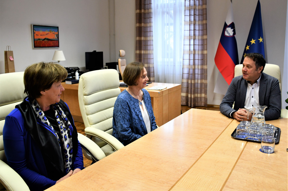 Milka Olip, mag. Martina Piko-Rustia, Matej Arčon. Sedijo za mizo.V ozadju zastave.