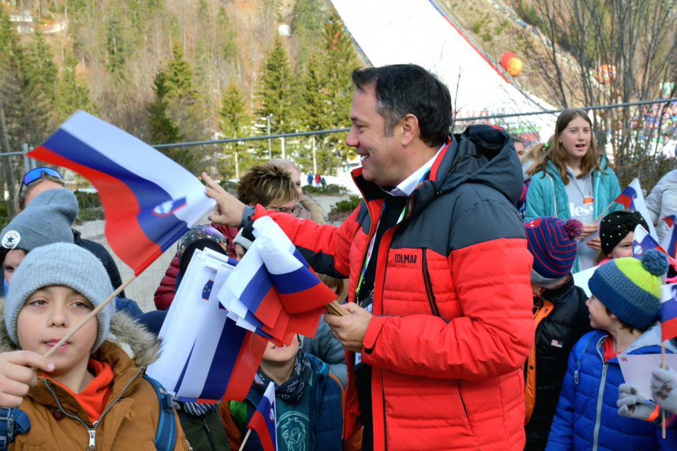 Minister Arčon deli otrokom slovenske zastave.