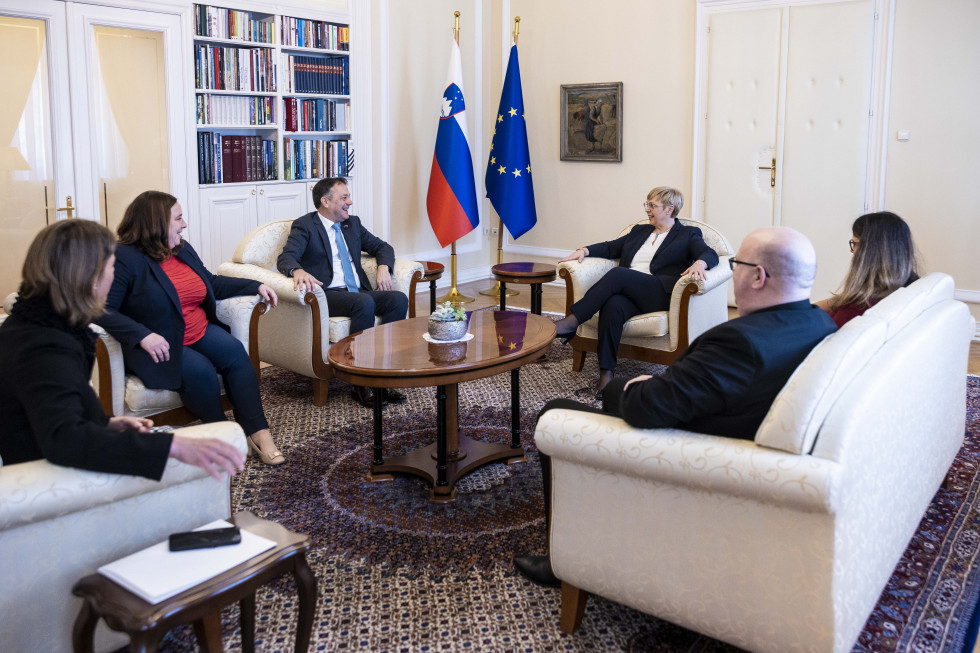 Minister Matej Arčon in državna sekretarka Humar s sodelavci. Sedijo na foteljih v predsedniški palači. v ozadju slovenska in evropska zastava.