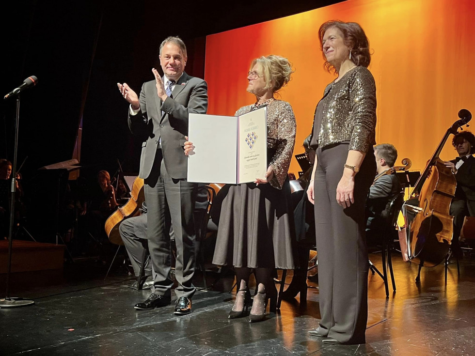 Matej Arčon, Franca Padovan, Alessandra Schettino na odru med podelitvijo priznanja. V rokah ga drži Franca Padovan, minister na levi ploska, Alessandra Schettino stoji ob Franci na desni. 