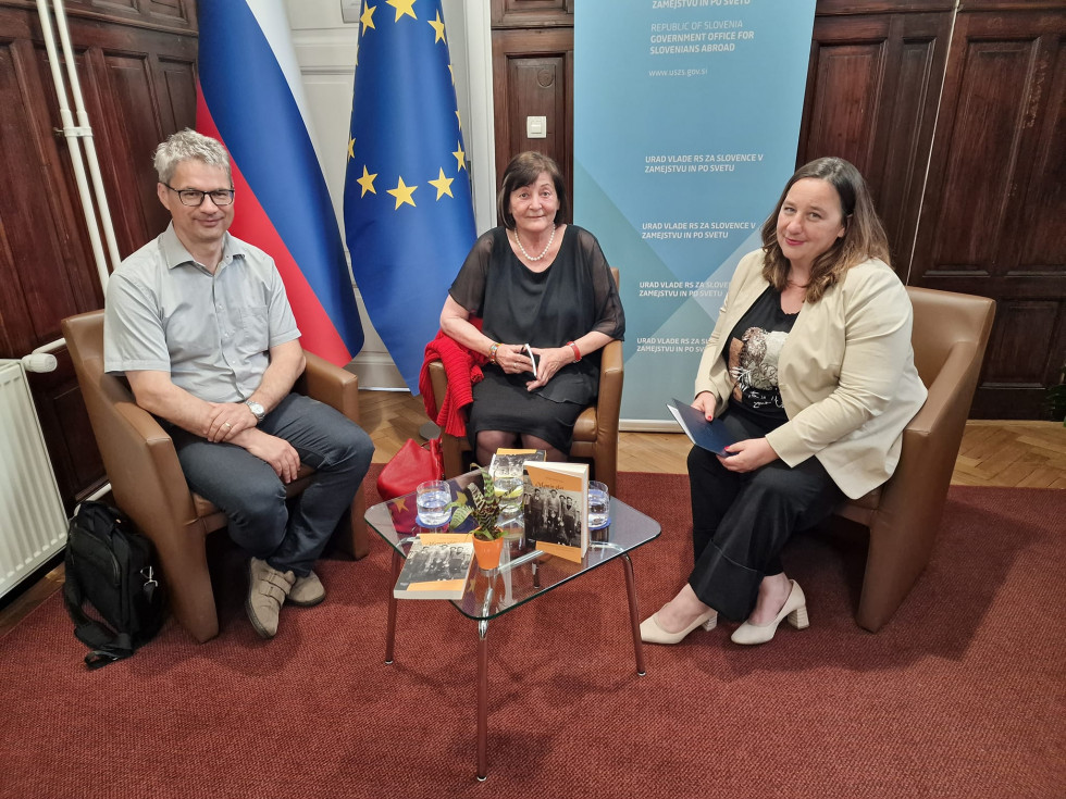 mag. Hanzi Filipič, dr. Helga Mračnikar, Vesna Humar sedijo za mizico, za njimi pano Urada in na desni slovenska in evropska zastava.