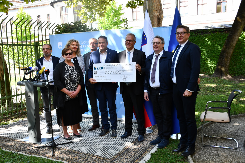 Pobudniki solidarnostne akcije z ministrom Arčonom in poveljnikom civilne zaščite Šestanom. Sojijo pred letakom urada, v rokah držijo ček.