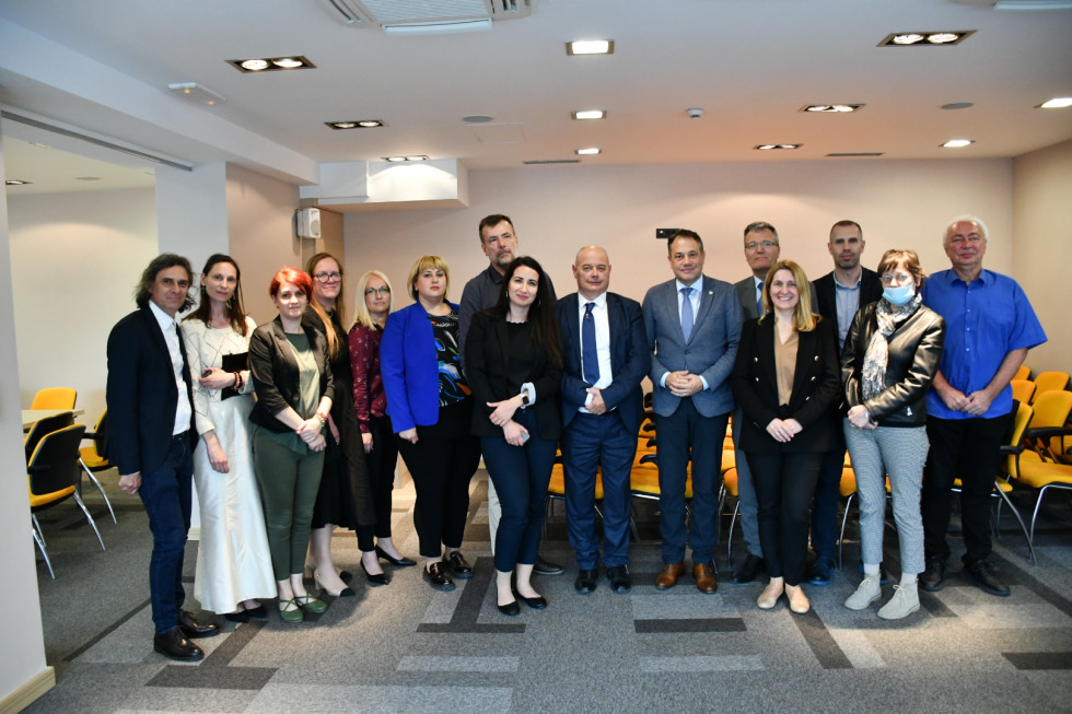 Minister, veleposlanik in predstavniki društev stojijo v dvorani.