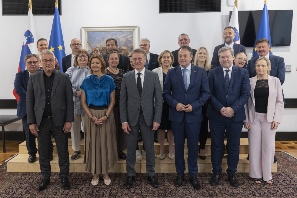 Skupinska fotografija članov, ob straneh evropske in slovenske zastave.