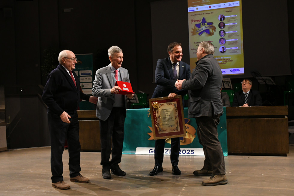 Minister Arčon med prejemom nagrade se rokuje s podeljevalci.