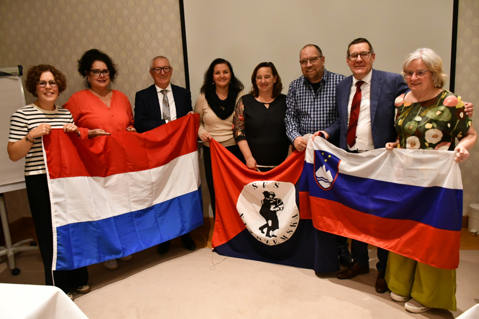 Skupinska slika, v rokah držijo slovensko, nizozemsko in zastavo društva.