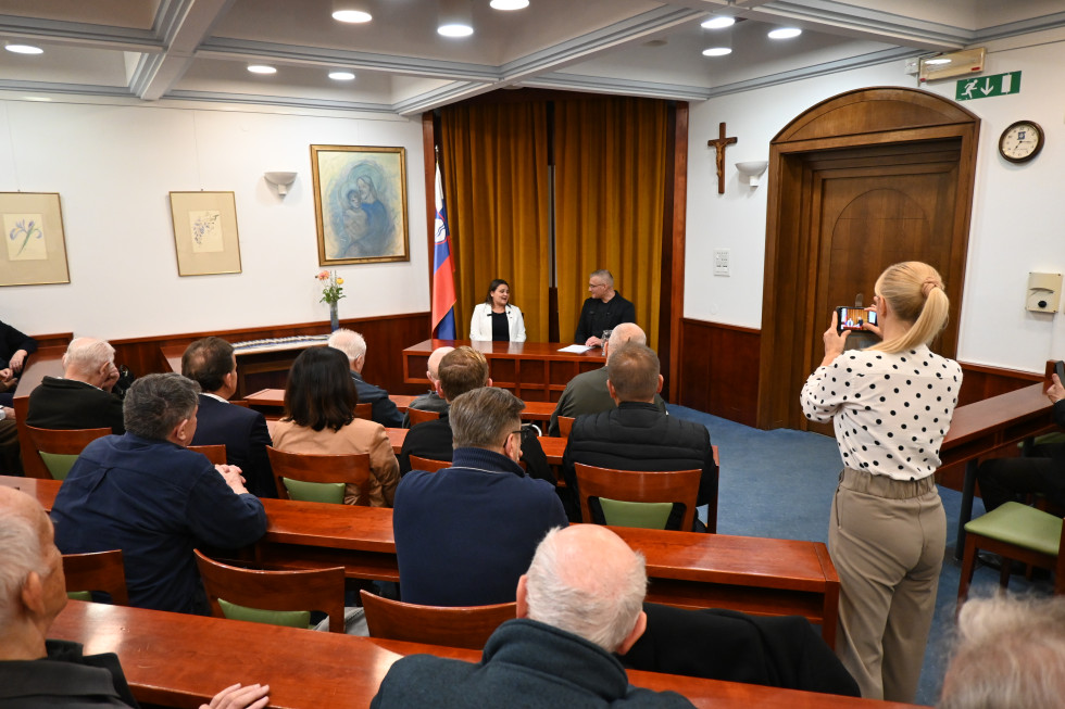 Dvorana, ministrica in g. Salihovič za mizo, na desni zastava.