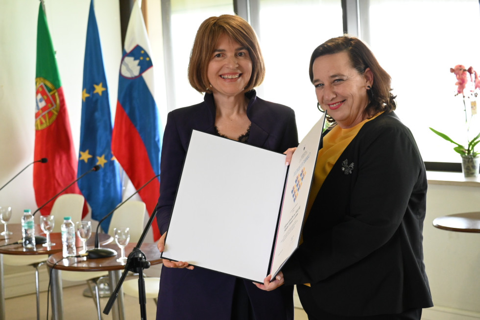 Držita priznanje, v ozadju zastave.