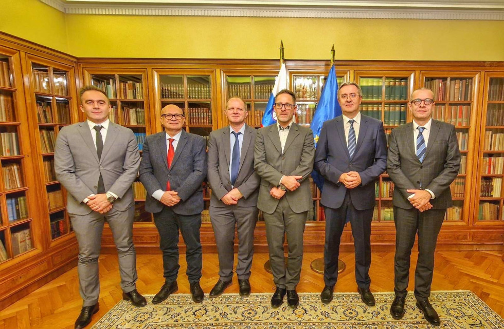 Direktorji nacionalnih varnostnih organov stojijo pred omaro, polno knjig, za njimi slovenska in evropska zastava